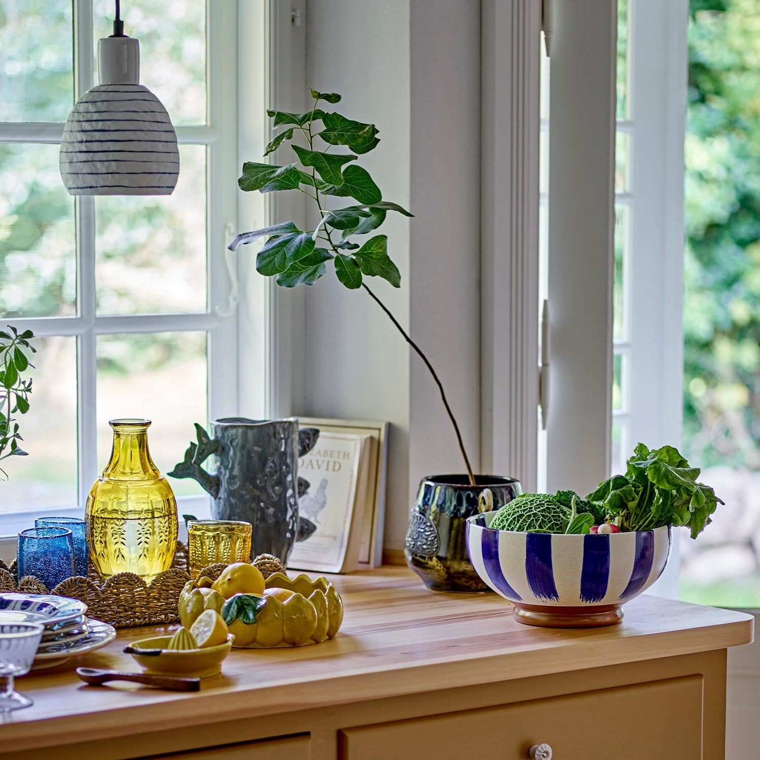 Decorative table setting with vases, bowls, and plants in a bright room.