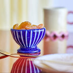 Blue striped bowl with dried fruits on a reflective surface
